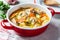 Chicken stew with potatoes and carrots in red saucepan. Chicken soup with vegetables and herbs. Comfort food recipe