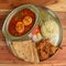 Chicken Thali from an indian cuisine, food platter consists Chicken fry,Boiled egg curry, lentils, jeera rice, and onions.