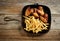 Chicken wings and fried potatoes on cast iron pan