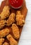 Chicken wings on a rustic wooden board with ketchup on white wooden background, top view. Close-up