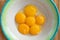 Chicken yolks lie in a white plate with a green border