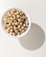 Chickpeas legume. Grains in a bowl. Shadow over white table.