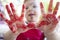 Chid boy showing his red stained hands after arts workshop for children. Closeup