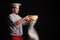 Chief cook is sifting flour through a sieve on black background