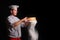 Chief cook is sifting flour through a sieve on black background