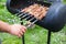Chief-cooker`s hands are grilling BBQ at home on an open fire, skewing metal sticks with juicy slices of meat. Summer picnic in