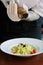 Chief hands dressing italian fettuccine pasta with pepper mill.