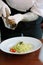 Chief hands dressing italian fettuccine pasta with pepper mill.