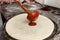 The chif pouring tomato sauce by ladle on a pizza