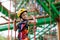 Child in adventure park. Kids climbing rope trail.