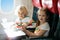 Child in airplane window seat. Kids flight meal. Children fly. Special inflight menu, food and drink for baby and kid. Girl and