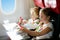 Child in airplane window seat. Kids flight meal. Children fly. Special inflight menu, food and drink for baby and kid. Girl and