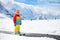 Child in alpine ski school with magic carpet lift and colorful training cones going downhill in the mountains on a sunny winter