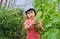 A child in amazement holding a large giant cucumbers in the greenhouse.