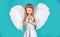 Child with angelic face. Cute child girl posing with angel wings. Beautiful little angel girl standing with your arms