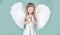 Child with angelic face. Cute child girl posing with angel wings. Beautiful little angel girl standing with your arms
