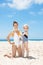 Child applying sunscreen on smiling mother in swimsuit at beach