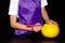 a child in an apron draws eye on a pumpkin. halloween concept.