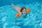 Child with armbands swimming in transparent blue water of pool