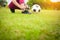 Child Asian tying shoes with ball on green grass.