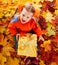 Child in autumn orange leaves and gift box.