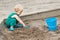 Child baby in sandbox playing with beach toys. Girl toddler digging sand and building sandpie. Kid have fun on playground. Summer