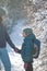 A child with a backpack walks with mother in a snowy forest