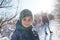 A child with a backpack walks with mother in a snowy forest