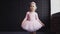 Child ballerina in pink tutu kavkazskoi looks blonde. Standing near the window and smiles. Slow motion
