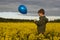 A child with balloon on field of flowers, northern summer