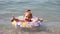 Child bathes in the sea with a life buoy. Girl with a life buoy swims in water