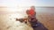 Child on the beach playing with sand and toys