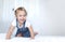 Child on a bed empty copy space background.Girl in white sheet in bedroom.Happy kid jumping on bed