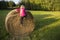 Child blond Girl by straw hay bale in field