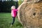 Child blond Girl by straw hay bale in field