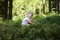 Child blond little girl picking fresh berries on blueberry field in forest.