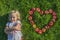 Child blond young Girl with red apples heart shape lying on the grass