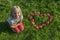 Child blond young Girl with red apples heart shape lying on the grass