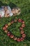 Child blond young Girl with red apples heart shape lying on the grass