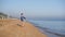 Child with blonde hair is playing with rocks on a sandy sea beach.