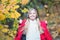 Child blonde long hair walking in warm jacket outdoor. Girl happy in red coat enjoy fall park good weather. Child wear