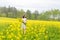 A child in a blooming field with yellow flowers.