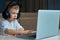 A child with blue eyes wearing headphones using a touchpad controls a laptop