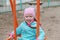 A child in a blue jacket swings on a swing. Happy five-year-old girl with pigtails having fun on the playground