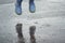 child in blue rubber boots jumping over the puddle in the rain