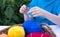 A child in a blue t-shirt is crocheting, and in a wooden basket, against the background of green leaves, there are colored skeins