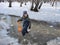 A child in blue waterproof pants, a jacket and a hat stands in a deep puddle. sunny day