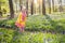 Child with bluebell flowers in spring forest