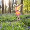 Child with bluebell flowers in spring forest