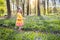 Child with bluebell flowers in spring forest